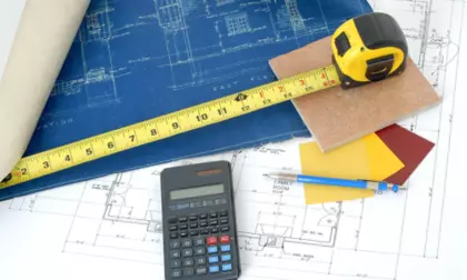 Bureau d'architecte avec une calculatrice, un mètre et des plans 2D