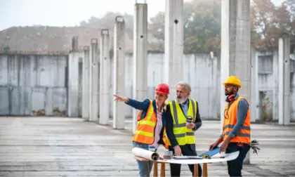 Trois personnes du bâtiment, habillées avec des EPI sur un chantier 